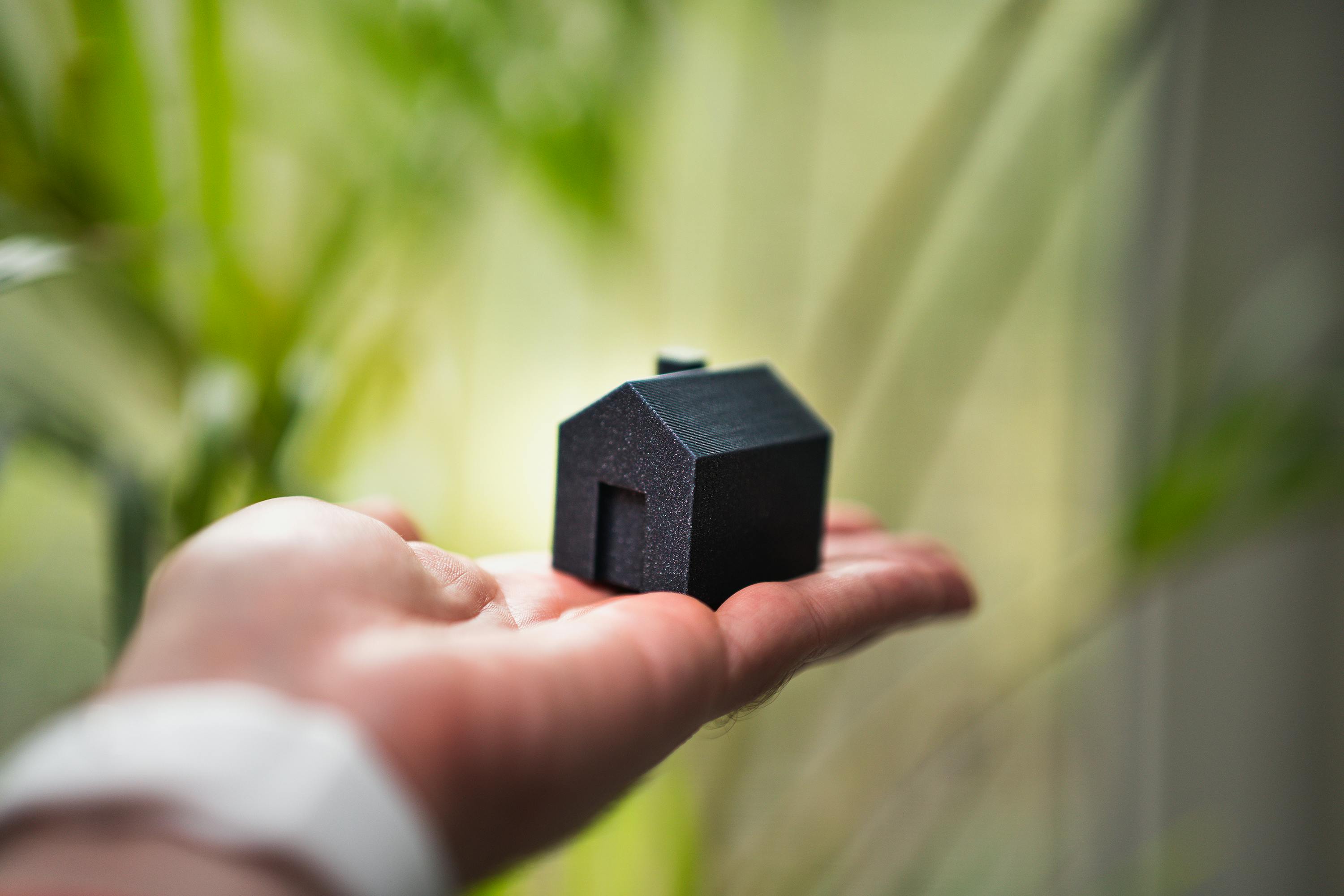 Hand holding a miniature house — philanthropic home for wealth management clients